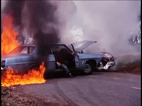 Man rolling out of burning car, 1970s Vidéo 64630032