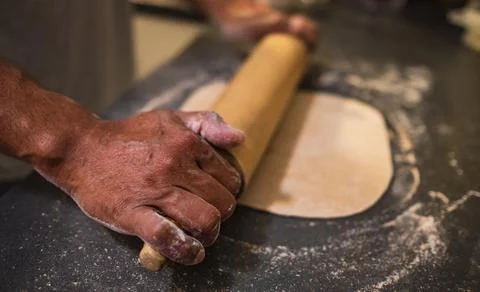 Man rolling out dough on kitchen table. Baking concept. Hands roll dough on b Stock Photos