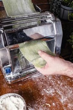 Man rolling out pasta to make spinach ravioli. Stock Photos
