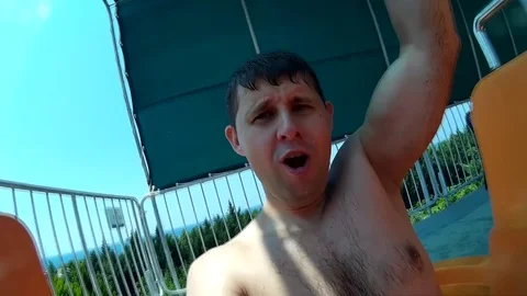 Man is rolling in the water slide. Man in the aqua park, shooting action camera. Stock Footage 77082413