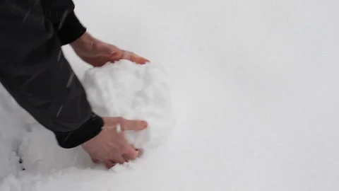 A man rolls a ball of fallen snow Stock Footage 122454255