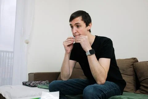 A man rolls a cigarette with both hands while sitting. The image reflects a Stock Photos