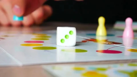 A man rolls a dice and moves a piece playing a board game Vidéo 145376555