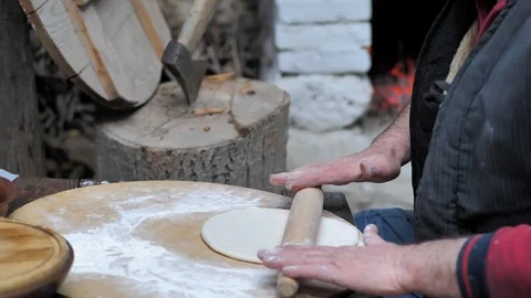 Man rolls dough with a rolling pin for baking flatbread in the medieval oven. Video stock 125504928