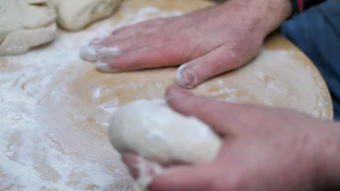 Man rolls dough with a rolling pin for baking flatbread in the medieval oven. Stock Footage 125504942