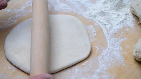 Man rolls dough with a rolling pin for baking flatbread in the medieval oven. Video stock 125504956