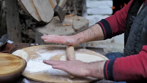 Man rolls dough with a rolling pin for baking flatbread in the medieval oven. Stock Footage 125529344