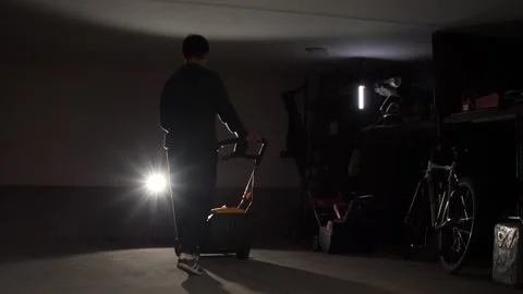 Man rolls lawn mower into garage. Grass mowing season is over Stock Footage 287124559