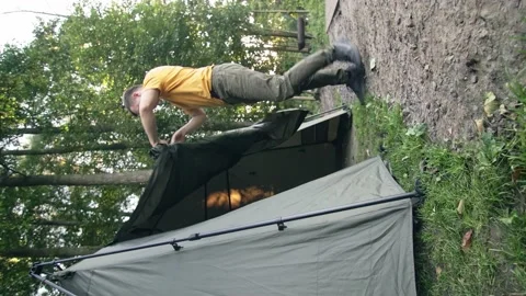 Man rolls open tent door and locks it. vertical video Stock Footage 207431266