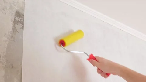 A man rolls out a canvas of white wallpaper. Removing air bubbles and glue from Stock Footage 197387947