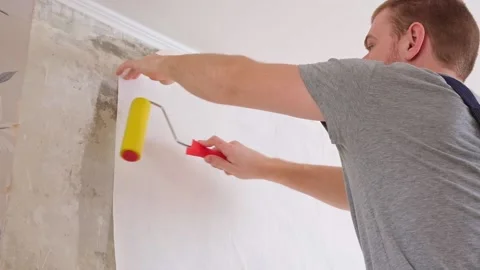 A man rolls out a canvas of white wallpaper. Removing air bubbles and glue from Stock-Footage 200917778