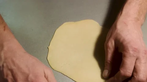 A Man Rolls out Dough on the Kitchen Table. Male Hands Roll Out the Dough. Stock Footage 230056560
