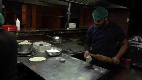 A man rolls out dough with rolling pin on a table sprinkled with flour 動画素材 242772893