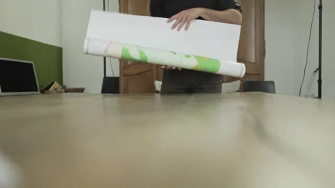 Man rolls out a map on a table 스톡 동영상 133494631