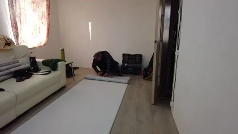 Man rolls out white paper on the floor in a room in the afternoon Stock-Footage 332563690