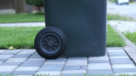 Man rolls a trash can from his plot of land onto the street. Waste removal 스톡 동영상 280942703