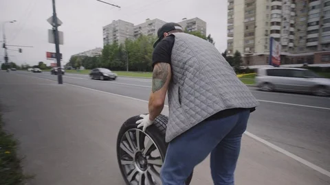 A man rolls a wheel on the road. Stock Footage 93026480