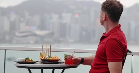 Man at Rooftop Bar with Cocktail Looking at Hong Kong Skyline Video stock 327689812