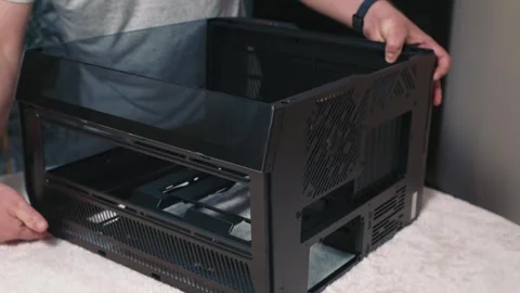 Man rotates computer case to show bottom section and ventilation grills 스톡 동영상 324592096
