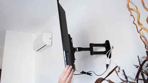 A man rotates a flat-screen TV hanging on a bracket, demonstrating a wide angle Stock Footage 278547042