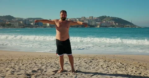 A man rotates his hands on the beach, morning exercises. Stock Footage 172141855