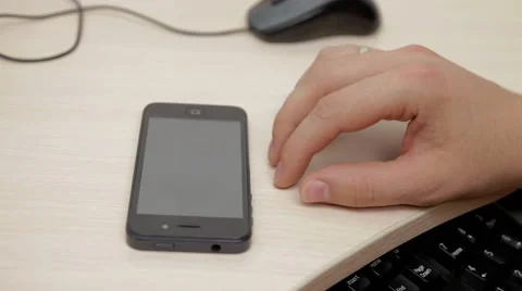 A man rotates phone on table Stock Footage 54354356