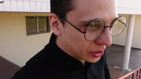 A man with round glasses says looking at the camera on the street Stock Footage 134776046
