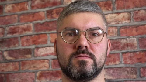 A man with round glasses with a serious face. Close-up 4K Stock Footage 150287101