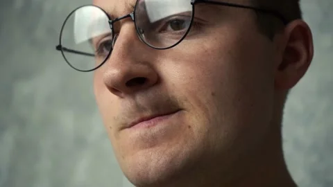 A man in round glasses sits working at the monitor Stock Footage 164307396