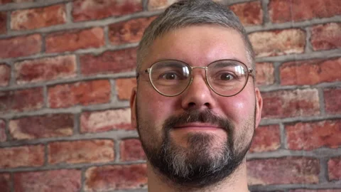 The man in the round glasses smiles. Close-up 4K Video stock 150287091
