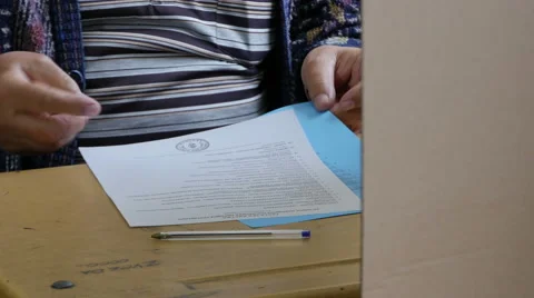Man rounding two electoral ballots and bending before inserting in box, close up Stock Footage 62632980