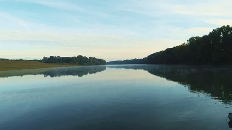 A man rowing in a boat in them middle of a river, filmed with a drone moving  Stock Footage 113068499