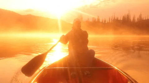 Man rowing canoe at sunrise Stock Footage 61669770