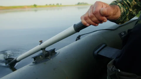 A man is rowing on an inflatable boat in search of a fishing spot Stock Footage 248441996