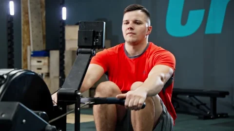 Man rowing on rowing machine in gym. Sportsman doing cross training indoors. Stock Footage 273199772