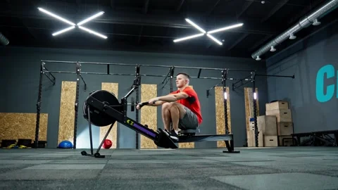 Man rowing on rowing machine in gym. Sportsman doing cross training indoors. Video stock 274389176