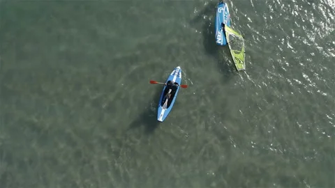 A man rowing on the sea with an oar while sitting on a surfboard Stock Footage 146247953