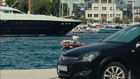 Man rowing small boat in marina near luxury yacht Stock Footage 340326802