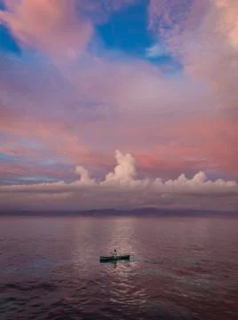 Man rowing a small canoe during sunset at Nusa Lembongan Island Foto stock