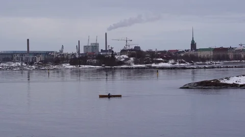 Man rows in the archipelago of Helsinki in the winter with snow and the city Stock Footage 103343726