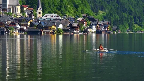 Man rows on the boat on the lake next to the Hallstatt village 스톡 동영상 79252427