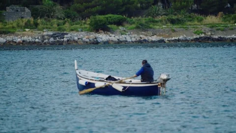 Man rows a small wooden boat across the sea, calm coastal rowing Stock-Footage 341587793