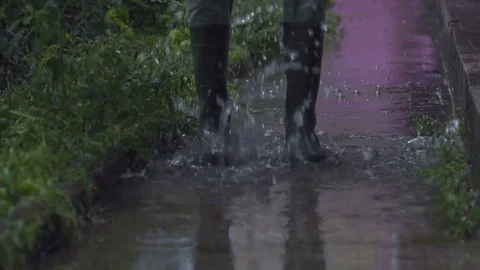 A man in rubber boots jumping over a puddle. Slow motion Stock Footage 78236667