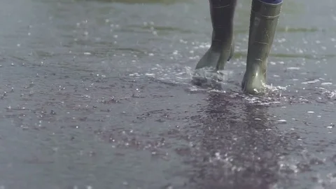 A man in rubber boots jumping over a puddle. Slow motion Stock Footage 78236668