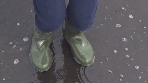 A man in rubber boots jumping over a puddle. Slow motion Video stock 78435514