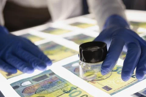 Man in rubber gloves checking authenticity of euro bills using lens closeup Stock Photos