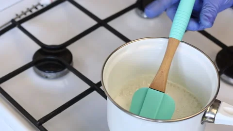 A man in rubber gloves stirs the boiling syrup for the zephyr with a spatula. Stock Footage 135159101