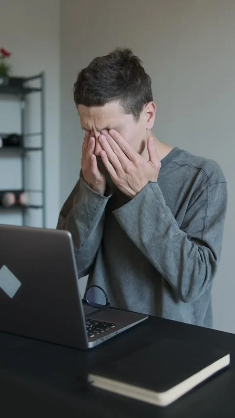 Man rubbing eyes while working on laptop. Tired eyes from long screen time.  Stock Footage 308237586