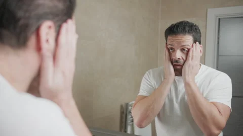 Man rubbing face in bathroom mirror Video stock 262072182
