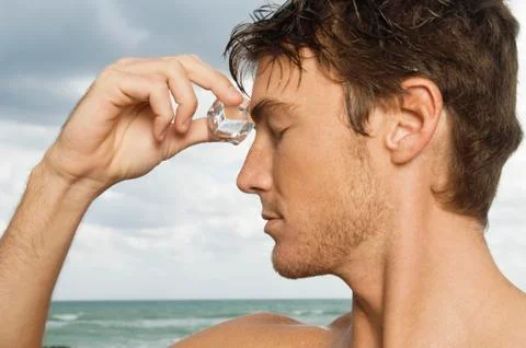 Man rubbing an ice cube on his forehead Stock Photos